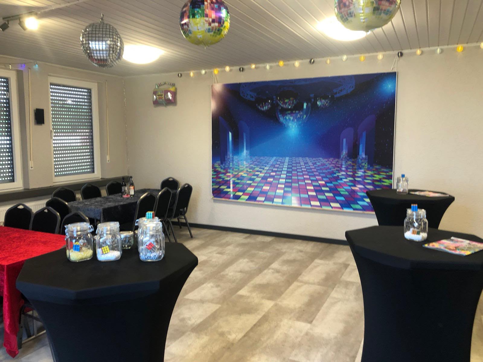 Partybereich mit schwarzen Stehtischen und farbenfroher Dekoration